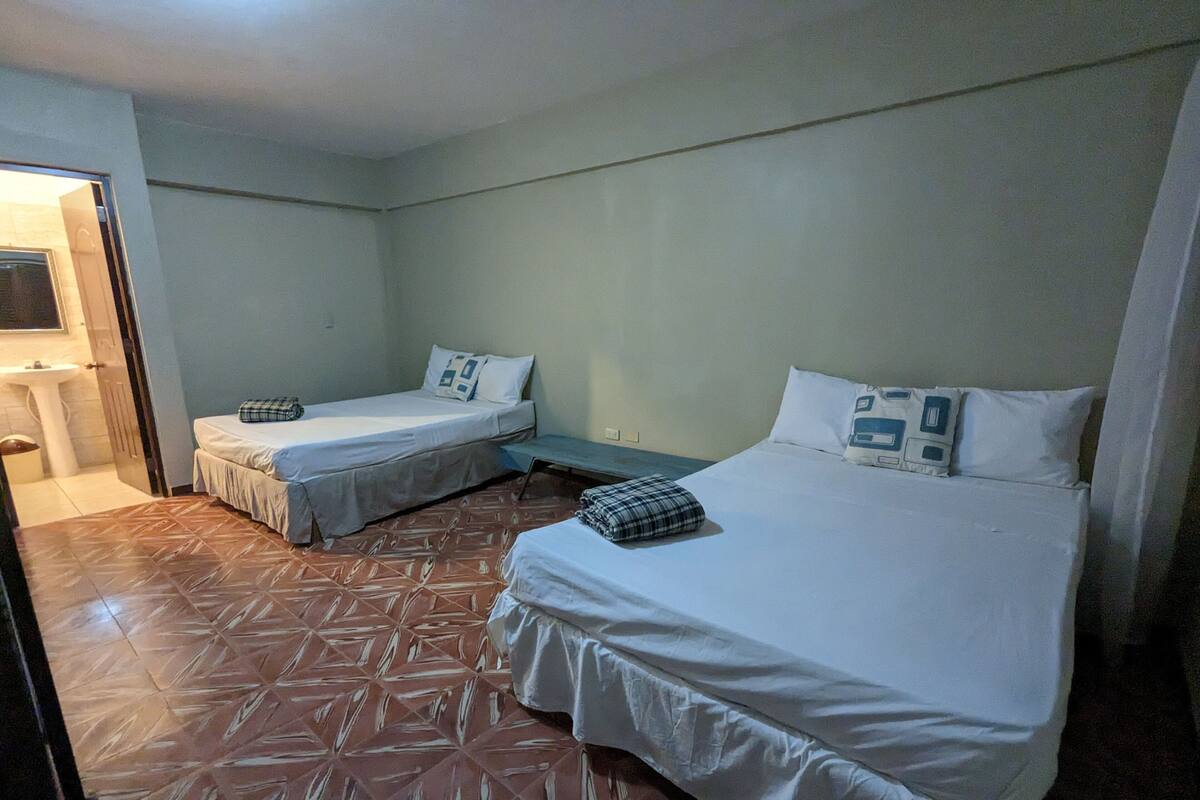 A room with two beds, a sink, and a patterned floor.