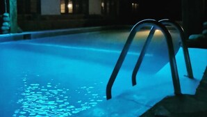 Une piscine la nuit, éclairée d’une lumière ambiante bleue.