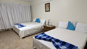 Une chambre d’hôtel avec deux lits, une table de chevet, une lampe et un tableau au mur.