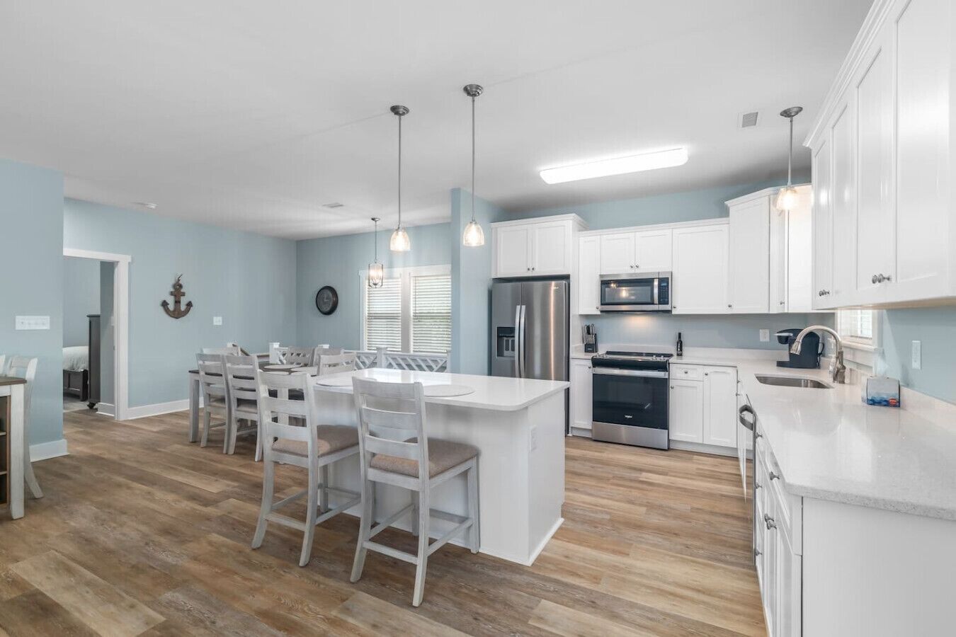 A modern kitchen with white cabinetry, stainless steel appliances, and a central island with bar stools.