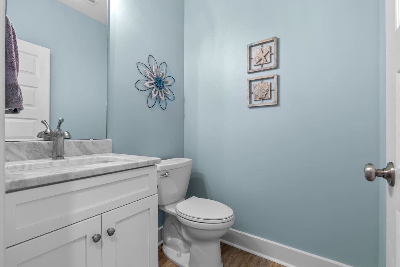 A bathroom with a white vanity, a sink, a toilet, and a blue wall.