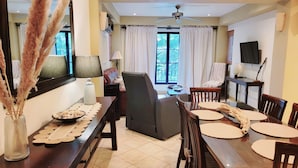 Un coin repas avec une table en bois, des chaises et un vase contenant des plumes d’herbe de la pampa.