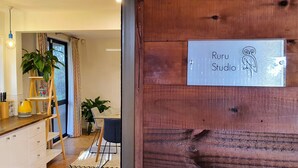 A kitchen with a sink, cabinets, and a window. There is a wooden door with a sign that reads "Ruru Studio". - Ruru Studio (Auckland)