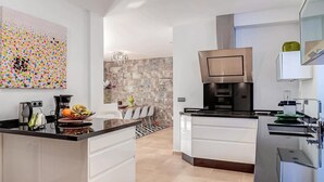 Una cocina moderna con una isla central, electrodomésticos de acero inoxidable y una pared decorativa de piedra.