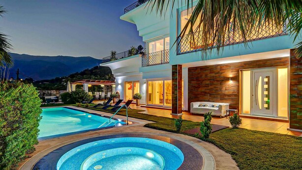 Una casa moderna con piscina, jacuzzi y un patio con sillones de descanso.