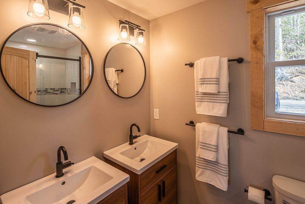 A bathroom with two sinks, a mirror, and two towel racks.