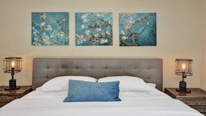 A bedroom with a bed, a grey upholstered headboard, white bedding, a blue pillow, and three wall-mounted paintings of branches with flowers. - Romantic Retreat w/ Private Pool. Near Las Olas (Fort Lauderdale)