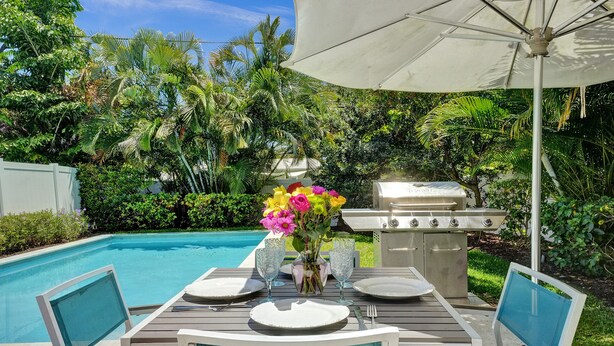 An outdoor dining area with a pool, surrounded by lush greenery and a barbecue grill. - Romantic Retreat w/ Private Pool. Near Las Olas (Fort Lauderdale)
