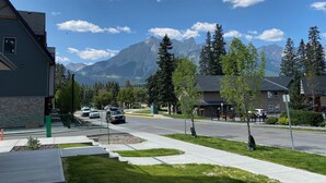 A residential street with houses, a clear sky, and mountains in the background. - Enchanted Mountain Getaway: Accessible Retreat in Canmore, Close to Banff (Canmore)