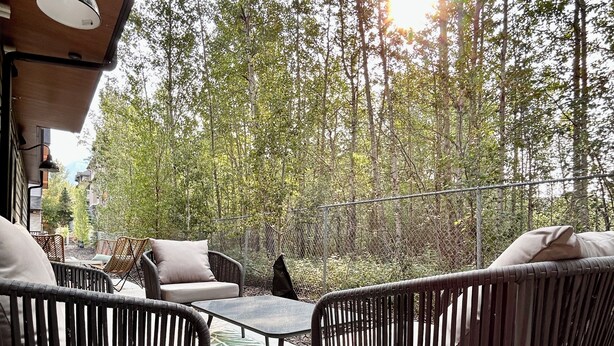 An outdoor seating area with wicker furniture and a green striped rug. - Enchanted Mountain Getaway: Accessible Retreat in Canmore, Close to Banff (Canmore)