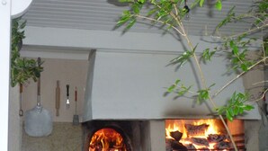 A brick oven with a fire burning inside, surrounded by a white metal fence. - Studio Proche Mer/montagne, Lieu Calme et Convivial (Santa-Maria-Poggio)