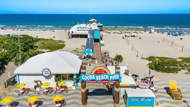 Un molo sulla spiaggia con un cartello che riporta 'Cocoa Beach Pier' e 'Westgate Resorts'.