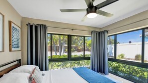 A hotel room with a bed, a ceiling fan, large windows, and a view of the outdoors. - Tranquil Getaway w/ Private Heated Pool (Fort Lauderdale)