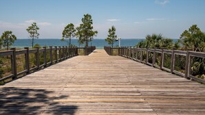 Un paseo marítimo de madera que conduce a una playa con vista despejada al océano.