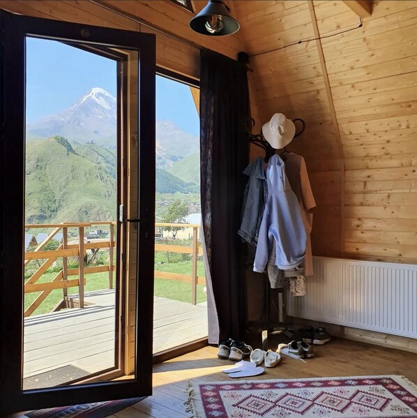 Ein Zimmer mit Holzvertäfelung, einem großen Fenster mit Bergblick, einer Kleiderpuppe und einem Teppich auf dem Boden.