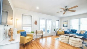 Ein geräumiges Wohnzimmer mit Holzboden, Deckenventilator, blauem Sofa und Couchtisch.