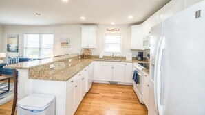 Eine moderne Küche mit weißen Schränken, einer Granit Arbeitsplatte und einem eingebauten Backofen.