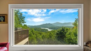 Habitación con un ventanal amplio que ofrece vistas a un paisaje boscoso y montañas.