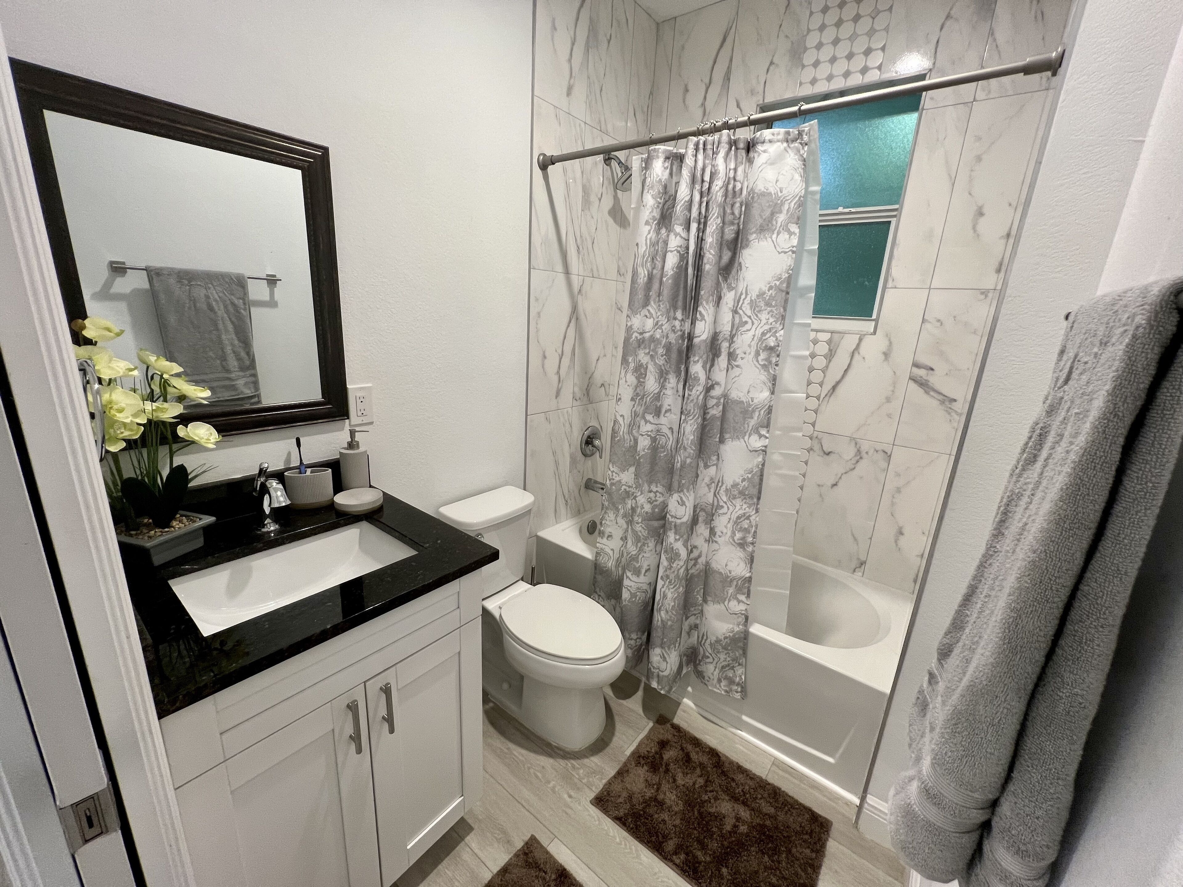 Un baño moderno con lavabo de superficie negra, inodoro blanco y cabina de ducha de vidrio.