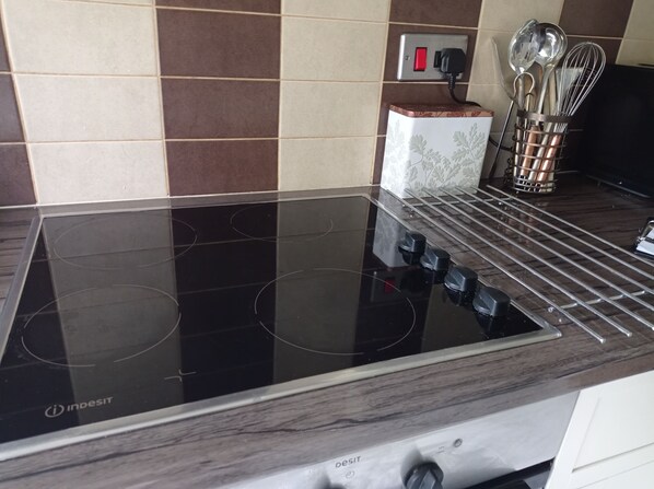 Una cocina con placa de inducción, toma de corriente y un portalapices.
