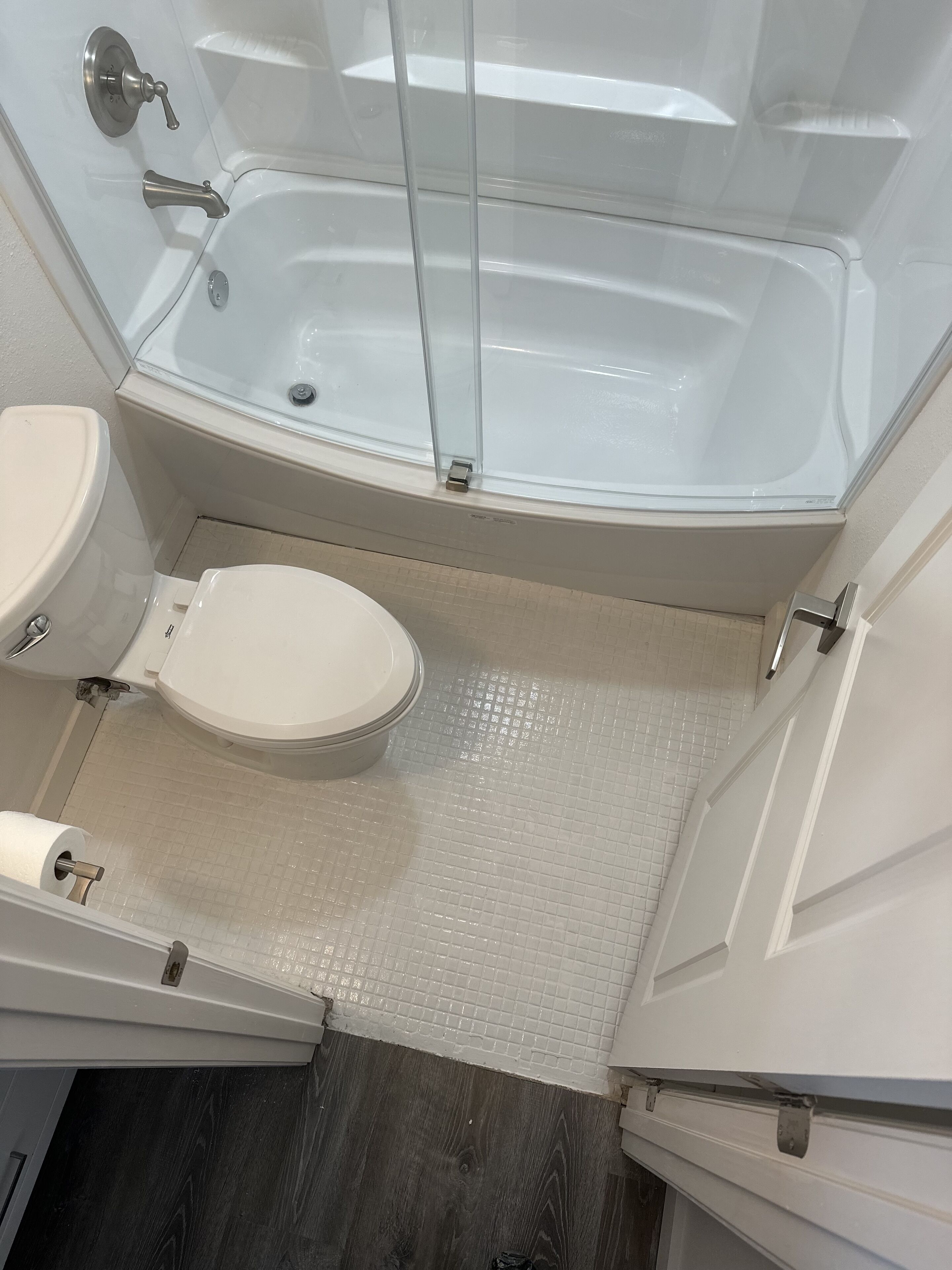 A bathroom with a glass-enclosed shower, a toilet, and a sink.