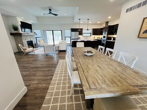 Una cocina moderna con comedor, que incluye una mesa de madera, sillas blancas y un cuenco de aperitivos.