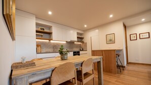 A modern kitchen with wooden cabinetry, a central island, and a dining area with chairs. -  Lake Front Living New and Cosy seperate ground floor appartment (East Jindabyne)