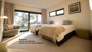 A bedroom with a large bed, a sofa, and a view of Lake Jindabye. -  Lake Front Living New and Cosy seperate ground floor appartment (East Jindabyne)