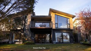 A modern two-story house with a flat ground floor, large windows, and a balcony. -  Lake Front Living New and Cosy seperate ground floor appartment (East Jindabyne)
