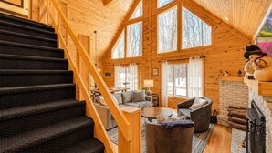 A spacious cabin interior with a wooden staircase, a fireplace, and a cozy seating area. - Beautiful Lodge in The Hideout!! (Lake Ariel)