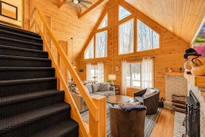 A spacious cabin interior with a wooden staircase, a fireplace, and a cozy seating area. - Beautiful Lodge in The Hideout!! (Lake Ariel)