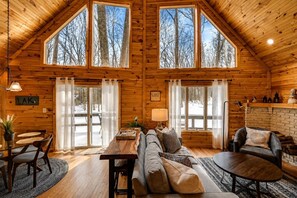 A log cabin interior with a dining area, sofa, and a fireplace. - Beautiful Lodge in The Hideout!! (Lake Ariel)