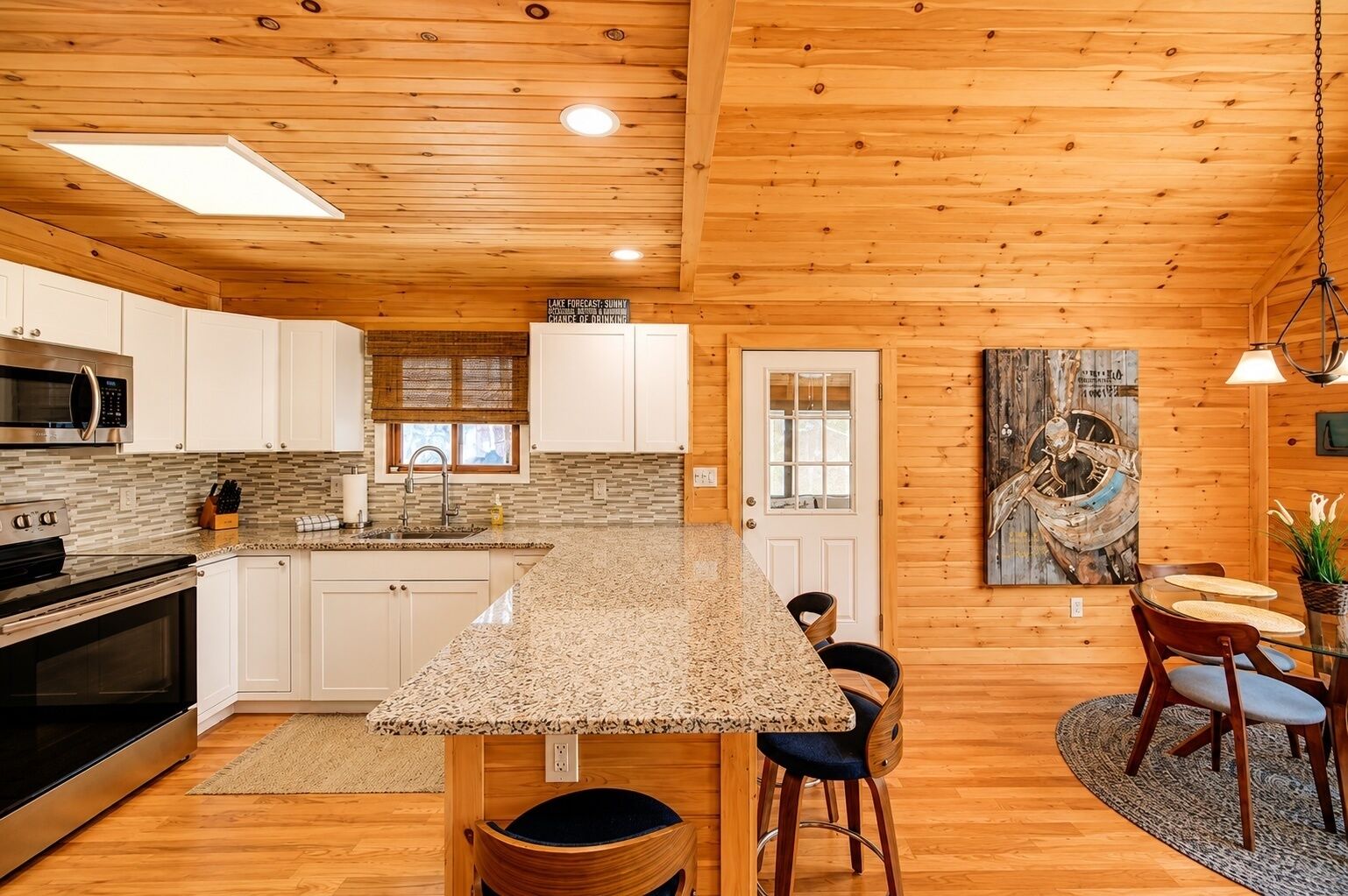 A kitchen with a granite countertop, white cabinets, and a wooden ceiling.