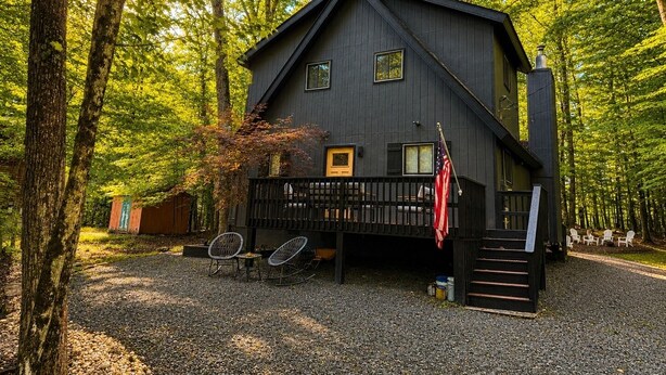 A cabin with a porch, outdoor seating, and a flag. - Beautiful Lodge in The Hideout!! (Lake Ariel)