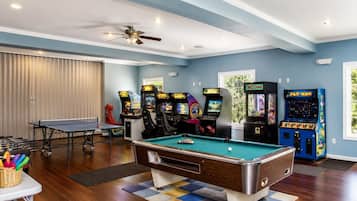 A recreational room with a pool table, arcade machines, and a ping pong table.