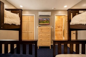 A room with bunk beds, a dresser, a TV, and an air conditioning unit. - Beautiful Lodge in The Hideout!! (Lake Ariel)