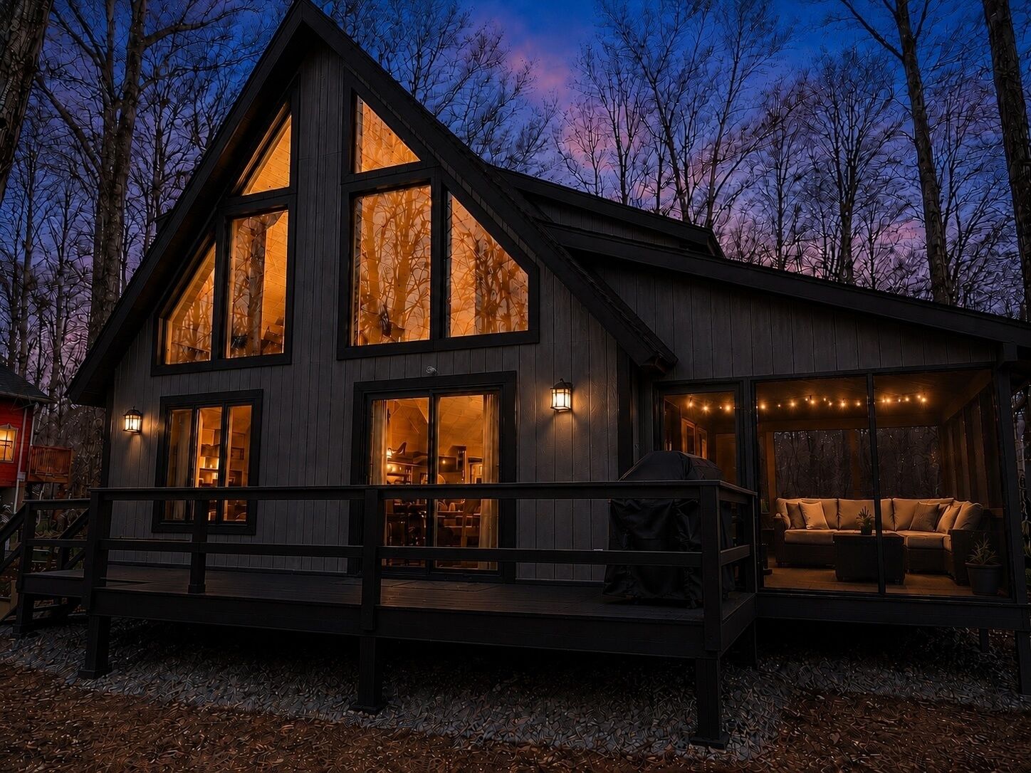 A two-story wooden cabin with large windows, a deck, and a cozy interior.