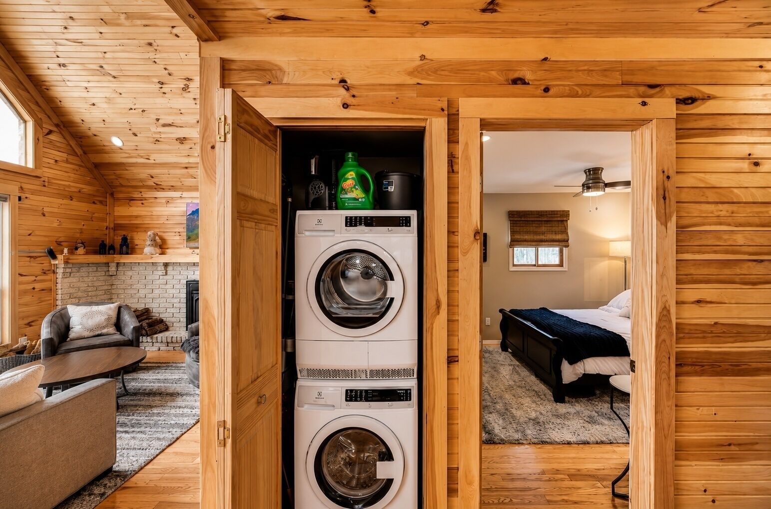 A compact room with a washing machine, a bed, and a small seating area.