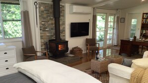 A cozy living room with a stone fireplace, comfortable seating, and a flat-screen TV.