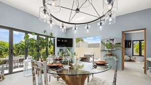 Un comedor moderno con una mesa de cristal, sillas rústicas y una lámpara colgante.