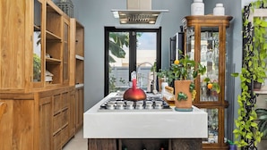 Una cocina moderna con una isla central, armarios de madera y vistas a través de la puerta.