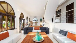 A spacious living room with a wooden coffee table, white sofas, and a view of the outdoors.