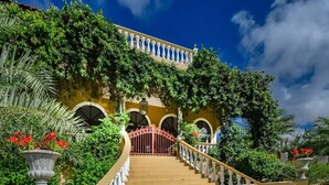A grand entrance with a staircase leading to a building with arched windows and a balcony.