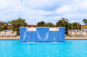 A swimming pool with a blue-tiled structure, palm trees, and lounge chairs. - 2BR Townhouse 3min walk 2 EagleBeach w/ Pool & BBQ (Oranjestad)