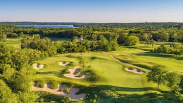 Stunning golf course with well-maintained fairways, sand bunkers, and lush greenery surrounded by dense forests and a serene lake.