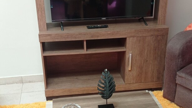 Un salon comprenant un meuble de rangement en bois pour l’équipement audiovisuel, un téléviseur à écran plat, une table basse et un canapé.