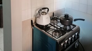 Une cuisine équipée d’une cuisinière à gaz, d’une bouilloire et d’une casserole sur le réchaud.
