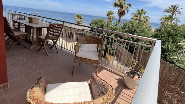 Ein Balkon mit Meerblick, Korbmöbeln und einer Topfpflanze.