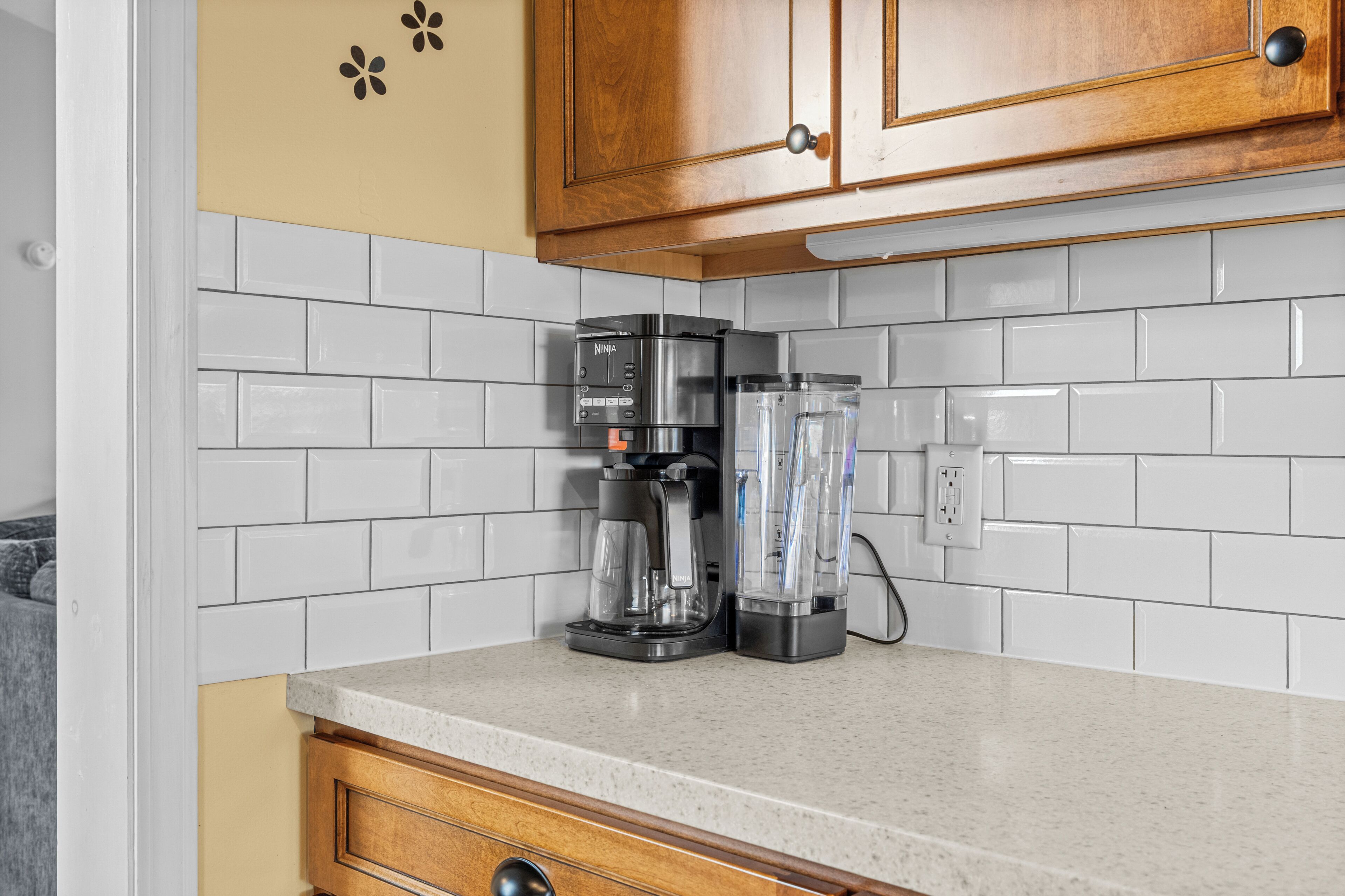 A kitchen with white subway tiles, a coffee maker, and a blender on the counter.