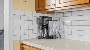 A kitchen with white subway tiles, a coffee maker, and a blender on the counter.